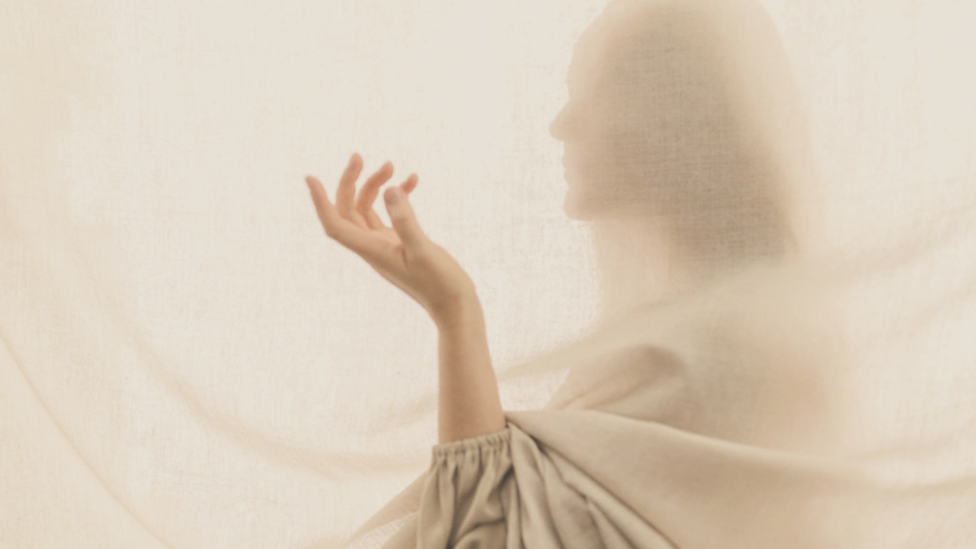 woman behind beige curtains holding her hand in a receiving way