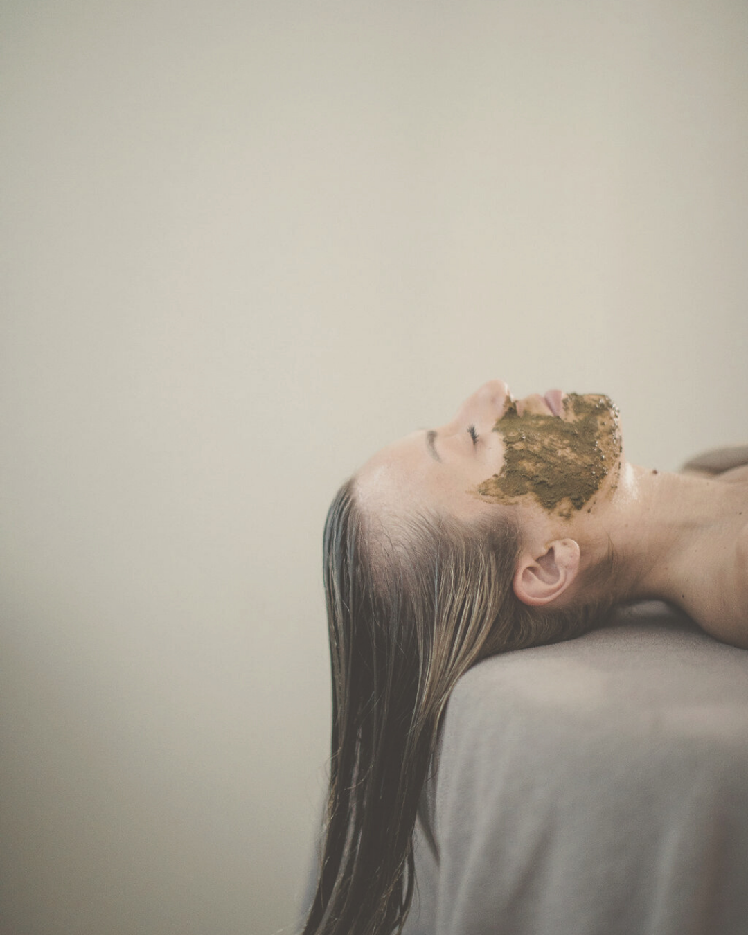 woman receiving Ayurvedic treatment with nourishing herb facial mask