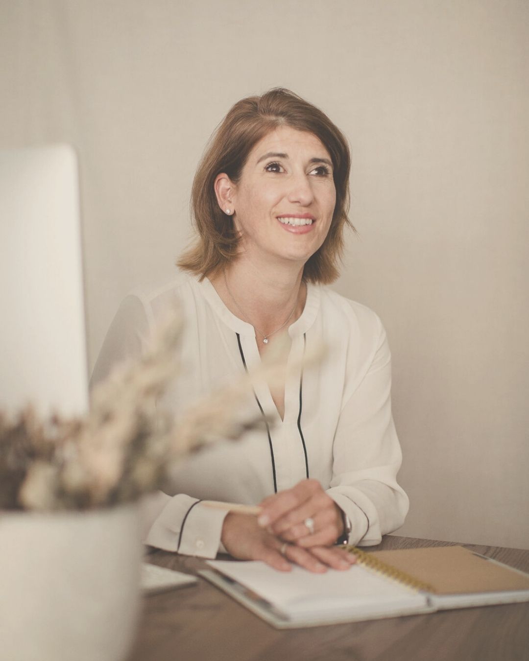 woman sitting at the desc in a beige atmosphere smiling 