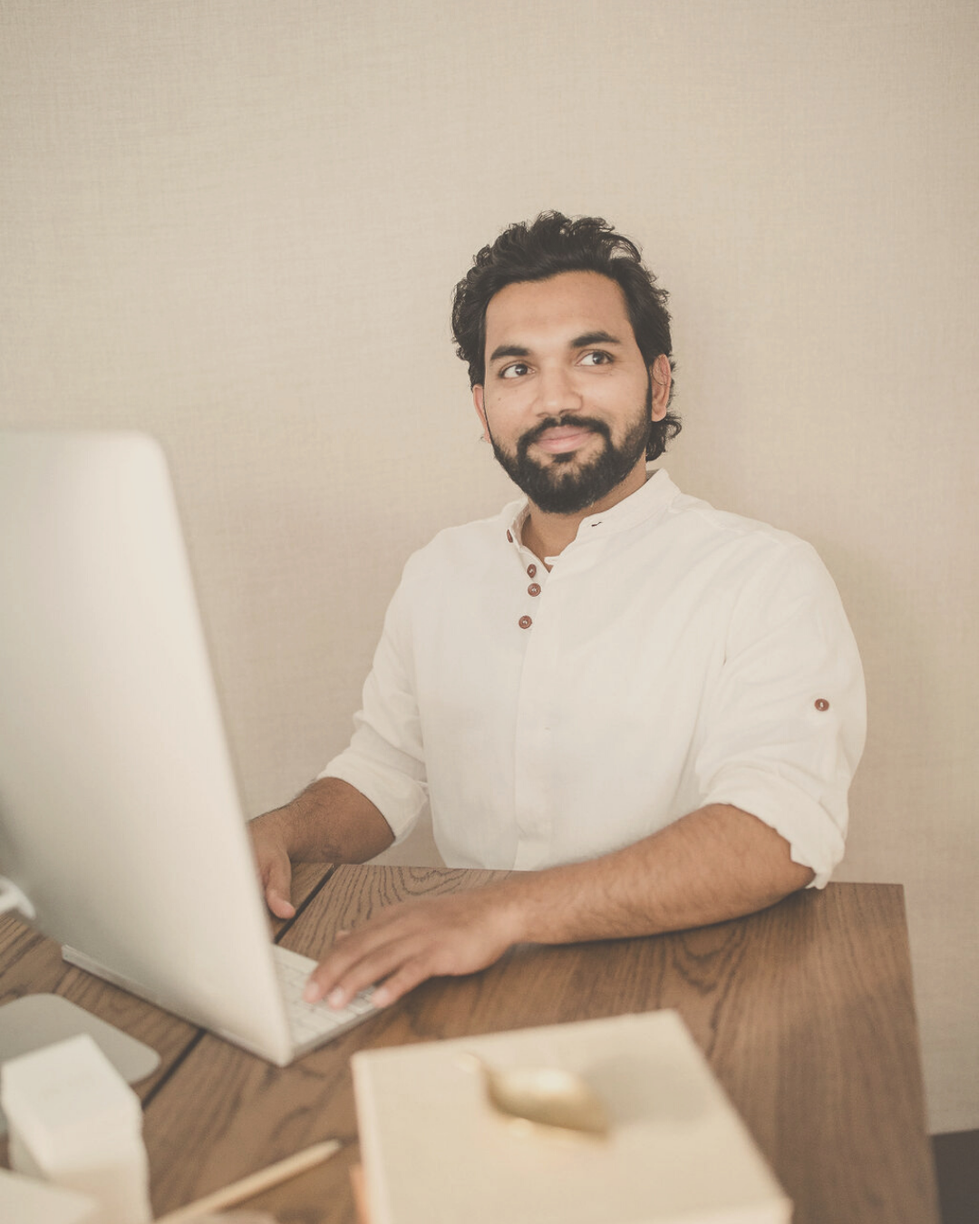 man sitting at a wooden desc smiling