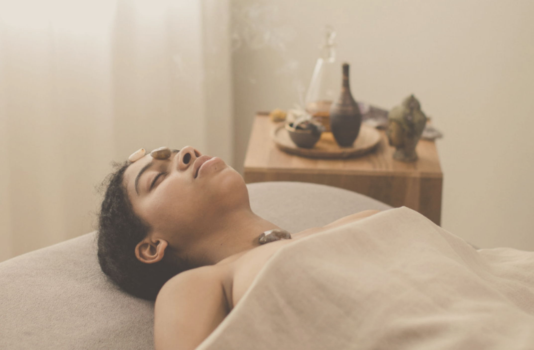 afro-american woman receiving energy healing treatment with healing crystals on her face and heart