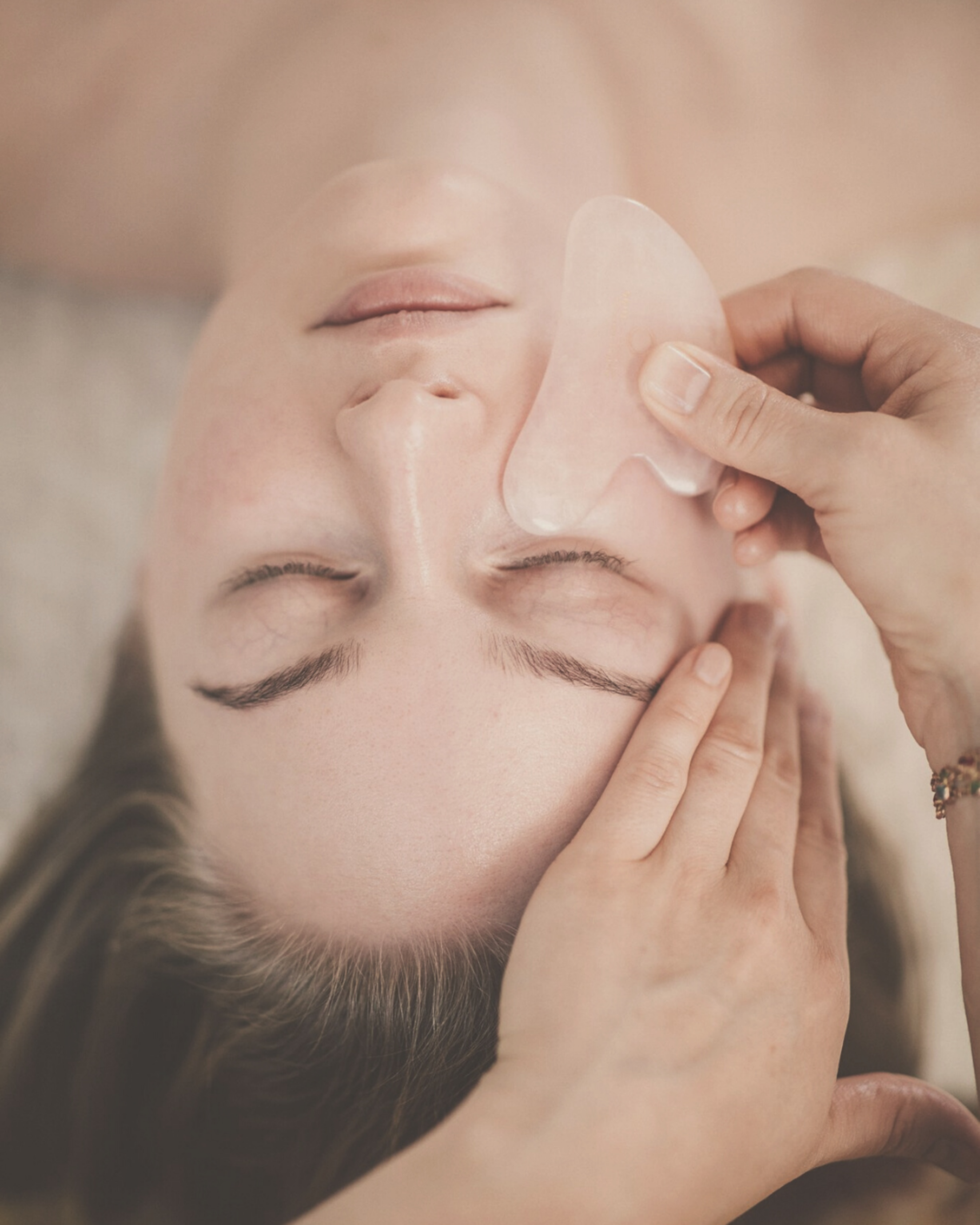 rose quartz gua sha tool held on women's face