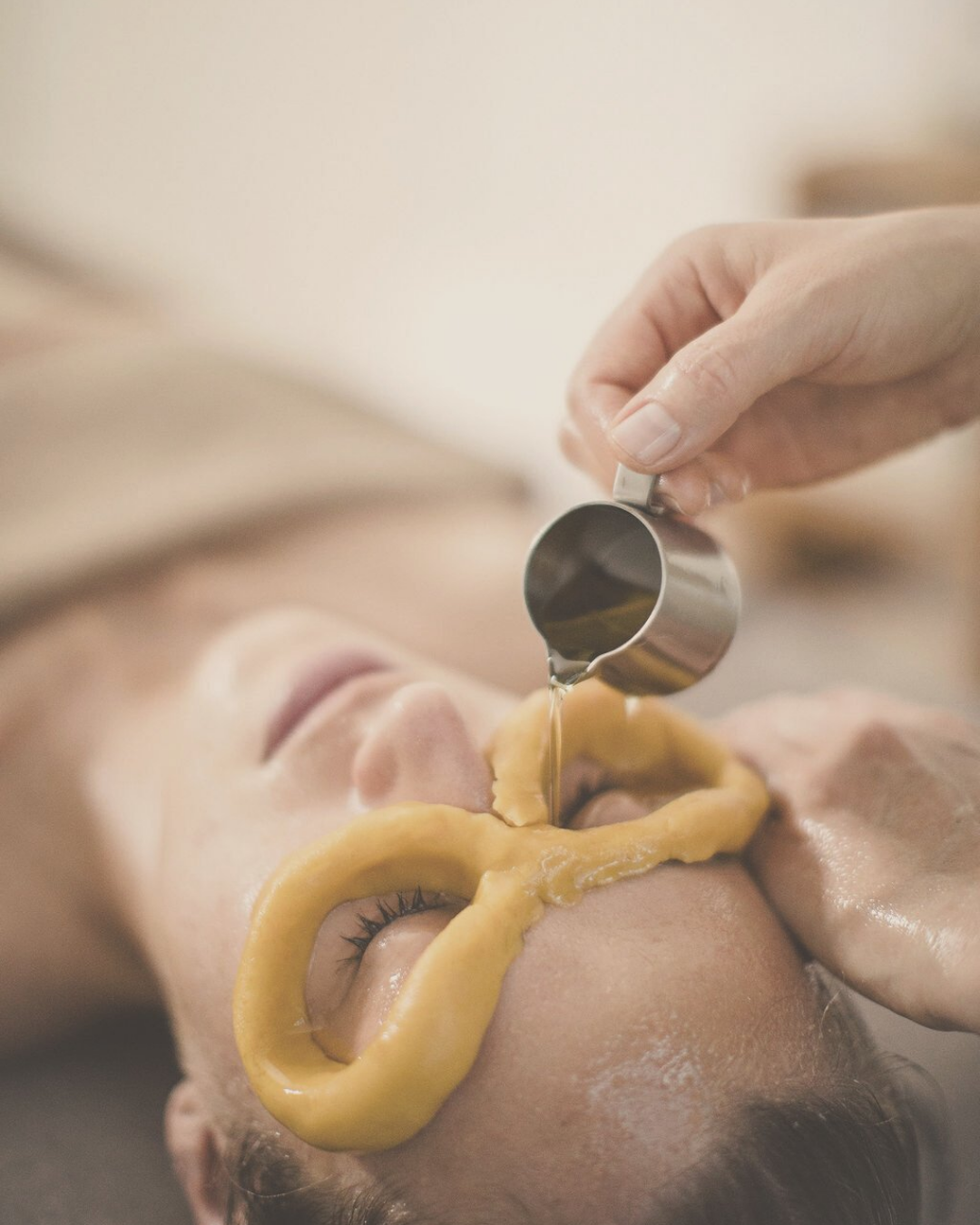 woman receiving Netra Tarpana - nourishing eye treatment with natural, medical, herbal oil that is poured into the eyes