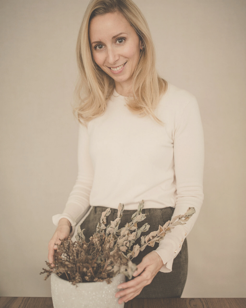 blonde woman arranging a dried flower bouquet smiling into the camera