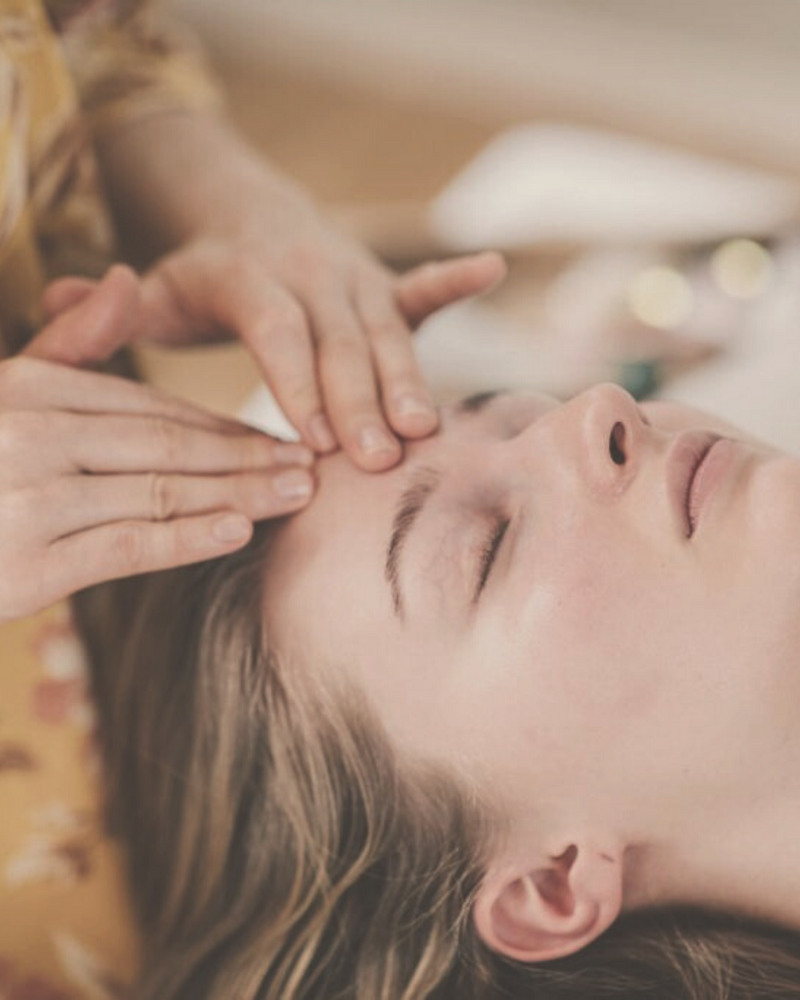 close-up of a woman's face receiving a rejuvenating facial marma therapy and energy healing 
