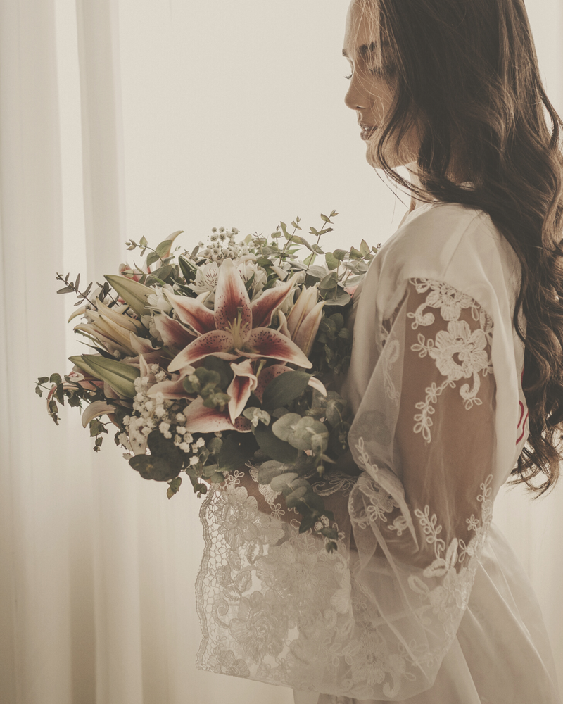 bride with brown long hair holding a bouquet of flowers looking at them