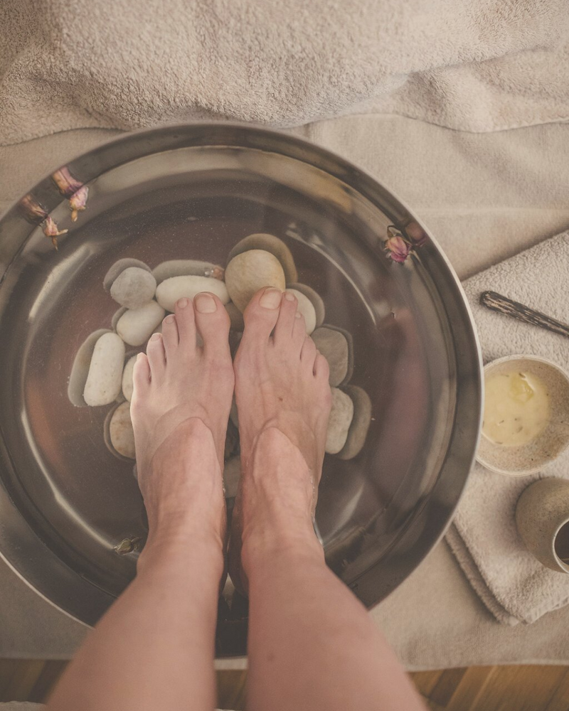 close-up of feet receiving a beautiful foot bath in a relaxing atmosphere surrounded by natural elements