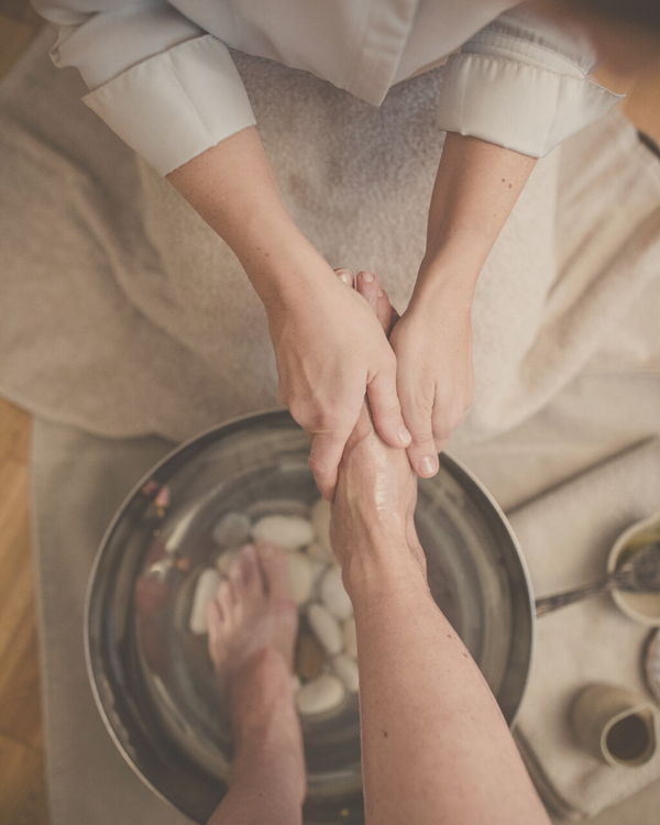 woman receiving a beautiful foot massage and foot bath with holistic and natural elements