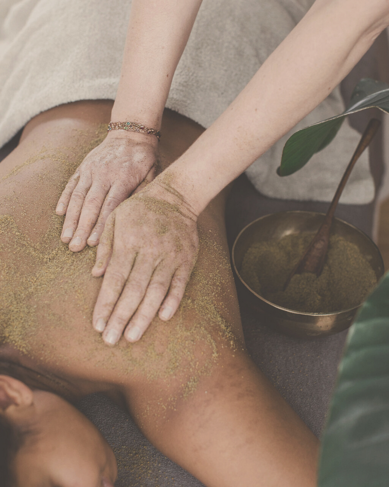 close-up of the back of a woman receiving a detoxing powder body massage, Ayurvedic Udvartana 